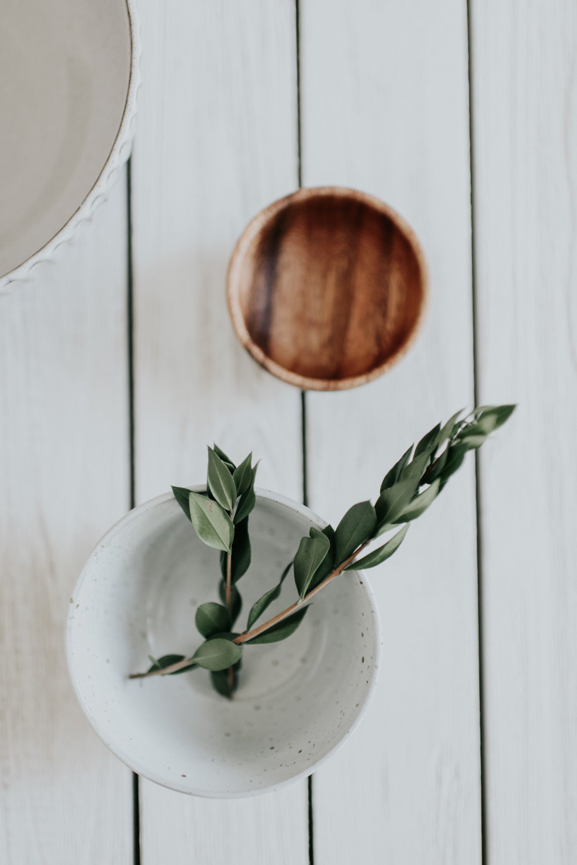 Stalk with Leaves on White Bowl by the Wooden Bowl